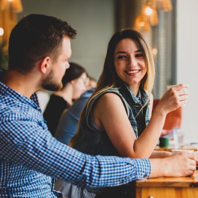 young couple sitting at a table in a cafe and drinking coffee